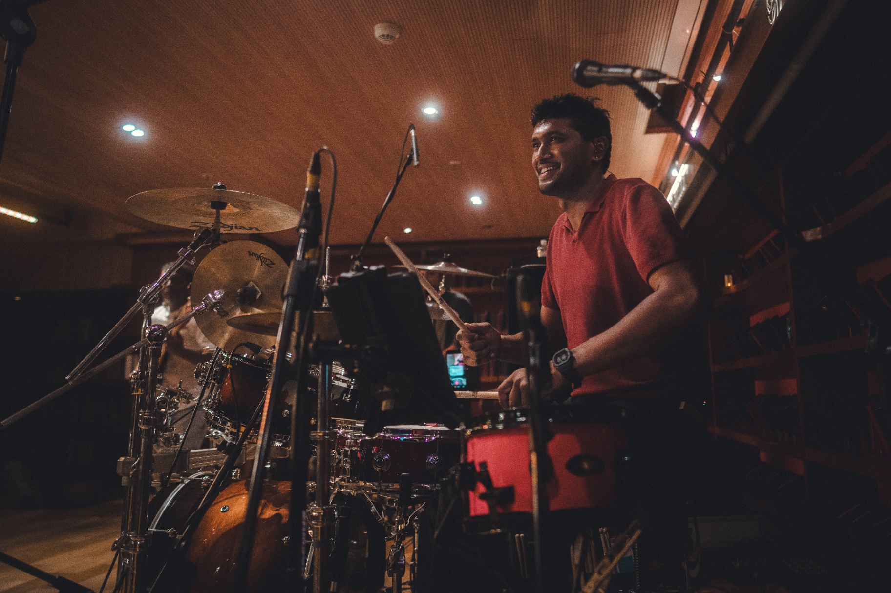 Drummachari smiling mid-performance behind the kit